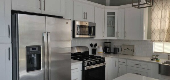 A modern kitchen with stainless steel appliances, white cabinetry, and a gas stove.
