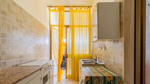A compact kitchen with a granite countertop, a small sink, and a microwave.