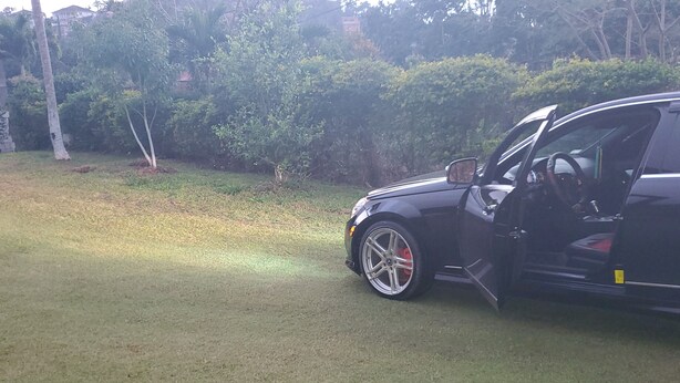 A black SUV parked on a grassy area with trees and bushes in the background. - Mckay's Home Away from Home (Hatfield)