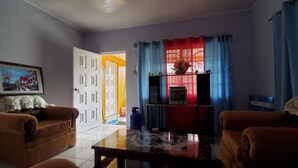 A living room with two sofas, a coffee table, a TV, and a door leading to another room. - Mckay's Home Away from Home (Hatfield)
