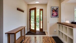 A hallway with wooden flooring, a bench, a coat rack, a door leading outside, and a shelf unit with a light fixture. - Ravens Roost--mountain views, hot tub, fireplace (Lyndhurst)