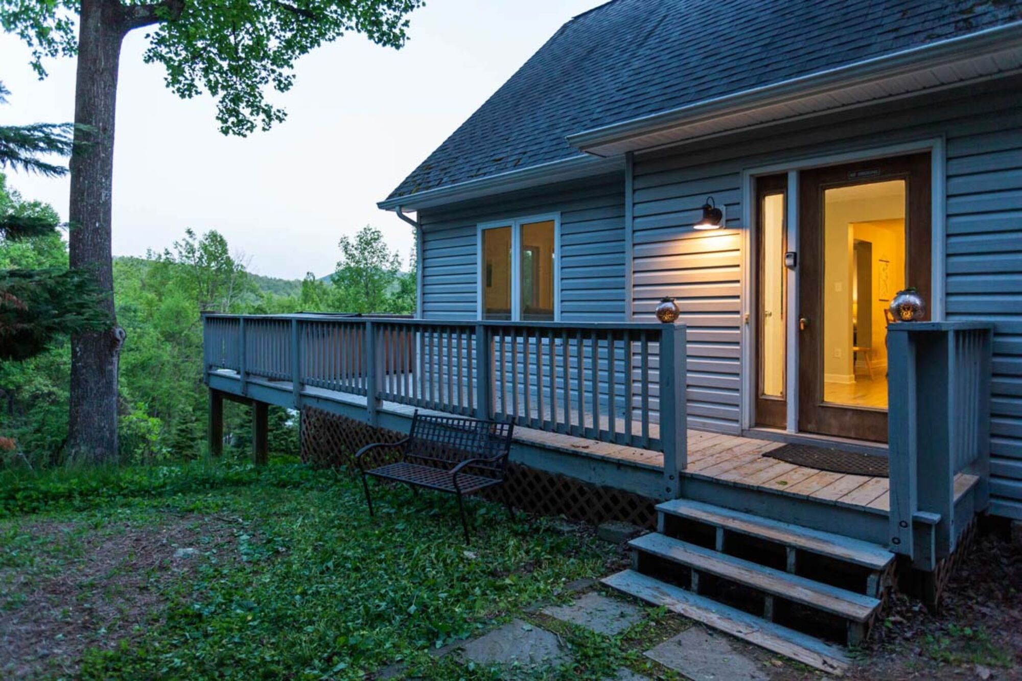 A house with a wooden deck, a bench, and a door with lights.