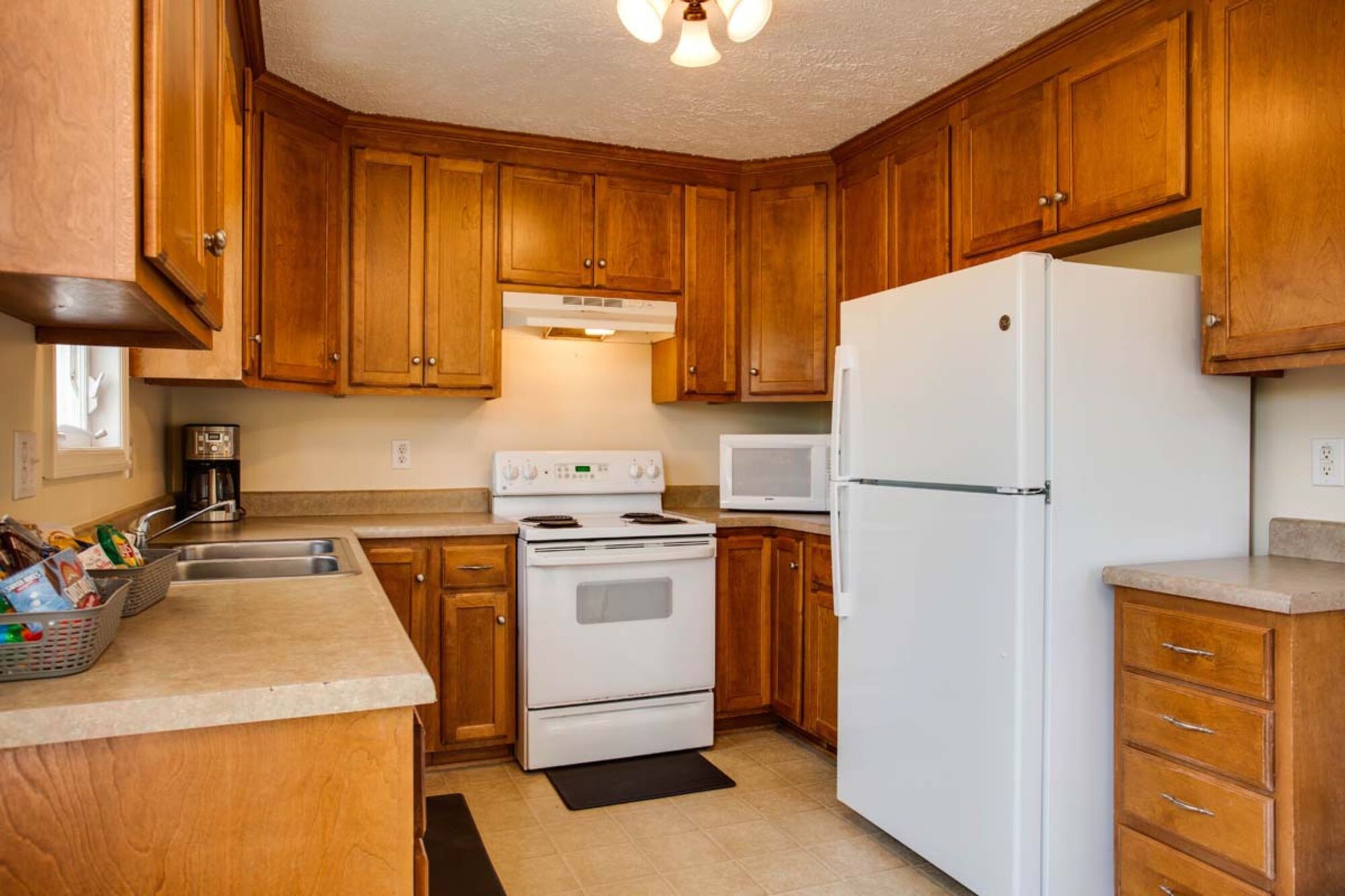 A kitchen with wooden cabinets, a white refrigerator, a stove, and a microwave.