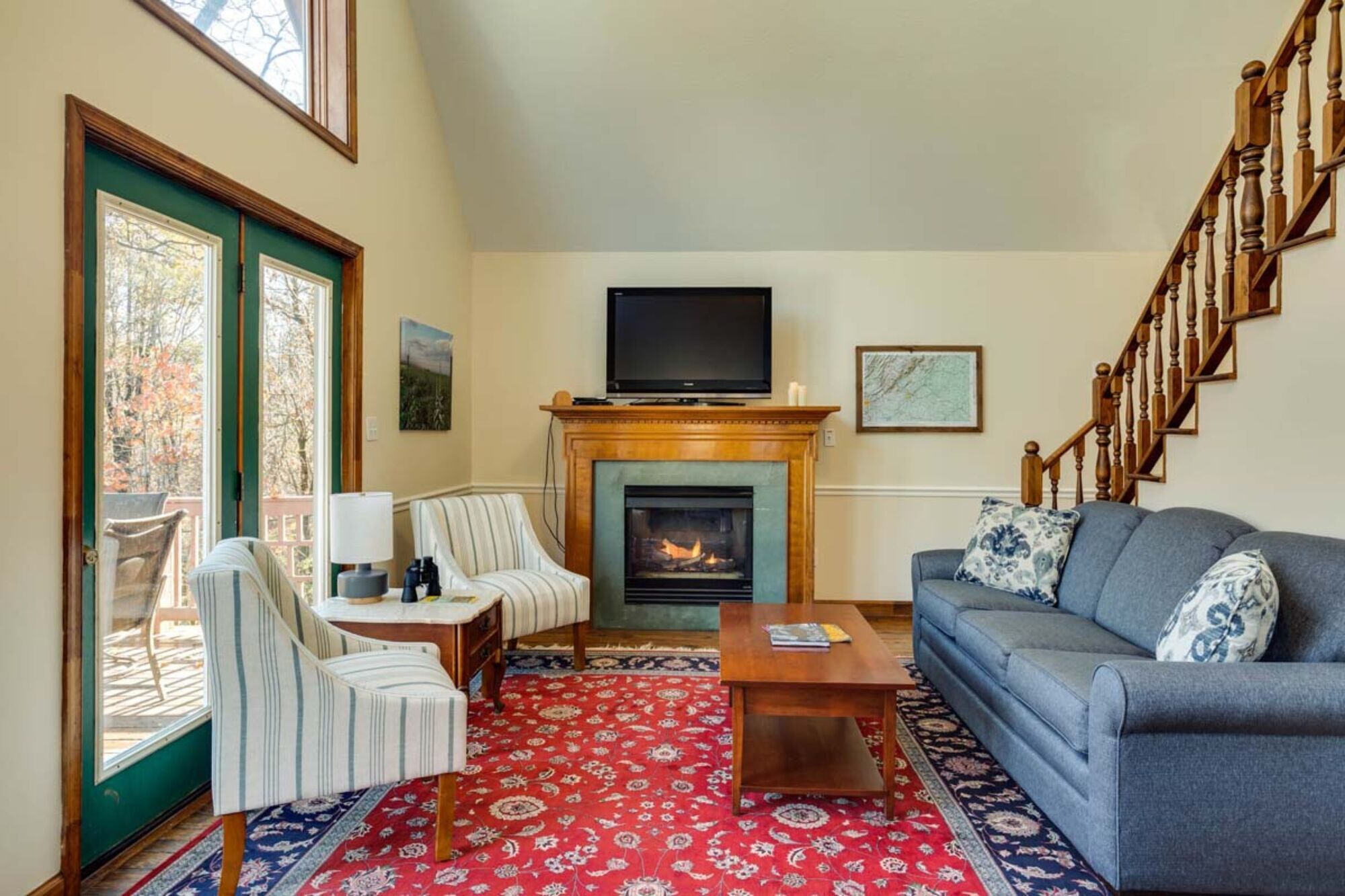 A living room with a fireplace, a television, a sofa, and a patterned rug.