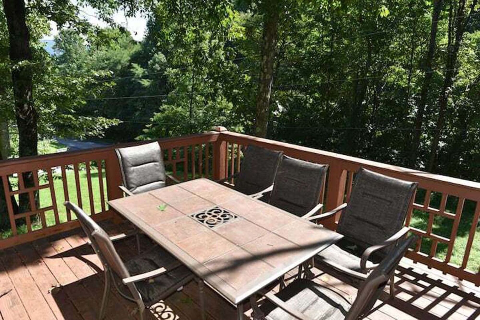 A wooden deck with a table and chairs, surrounded by trees.