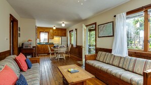 Un salon chaleureux avec un plancher en bois, un canapé, une table basse et un coin repas comprenant des chaises et une table.
