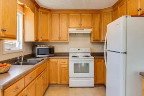 A kitchen with wooden cabinets, a microwave, an oven, and a refrigerator. - Torry Ridge--hot tub, mountain views, fireplace (Lyndhurst)