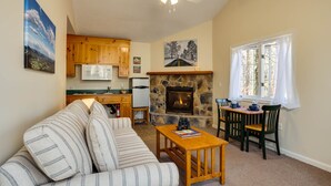 A cozy living room with a fireplace, wooden furniture, and a dining area with a view of the outdoors. - White Rock Cabin--1BR, ADA, kitchenette, fireplace (Lyndhurst)