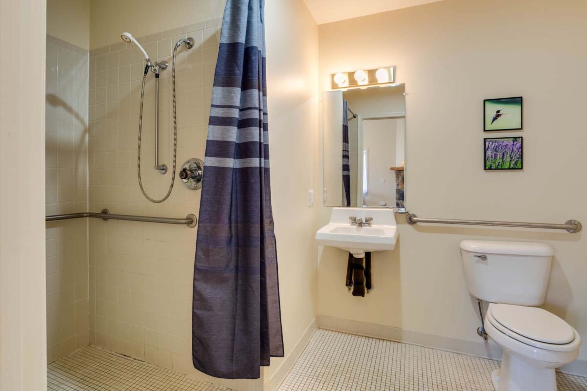 A bathroom with a shower, toilet, sink, and a mirror with lights.