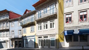 Une rangée d’immeubles à plusieurs étages dotés de balcons, un magasin fermé et une devanture visible avec une enseigne.