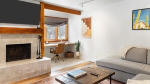 Una sala de estar moderna con chimenea, un sofá, una mesa de centro y un escritorio con una computadora.