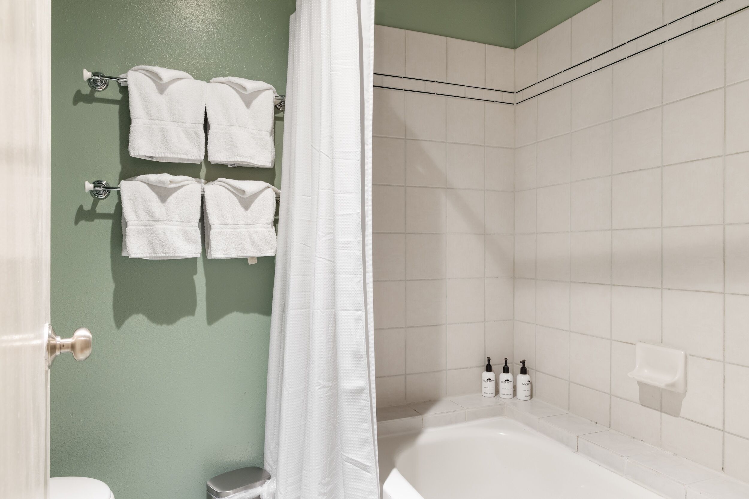 A bathroom with a bathtub, a shower curtain, and towels hanging on a rack.