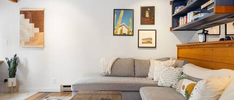 A modern living room with a grey sectional sofa, a wooden coffee table, and a bookshelf.