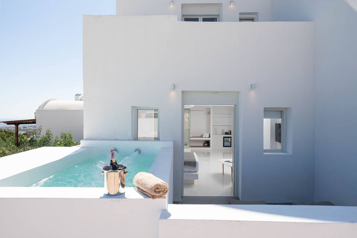 A modern white building with a rooftop infinity pool, a champagne bottle, and a towel.