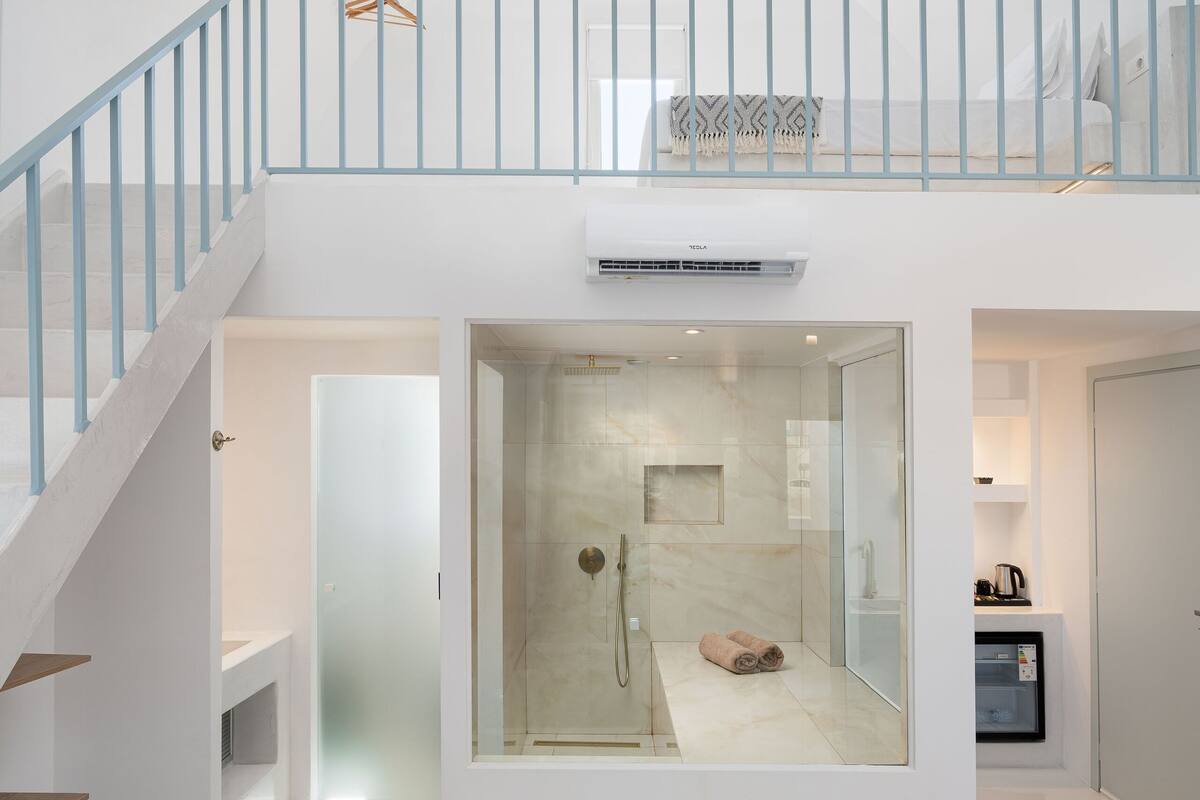 A modern steam room with a glass enclosure, a towel on the floor, and a sign indicating its name.
