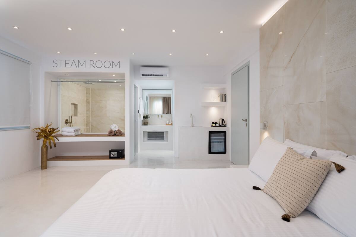 A modern steam room with a glass door, a mirror, and a small shelf with towels.