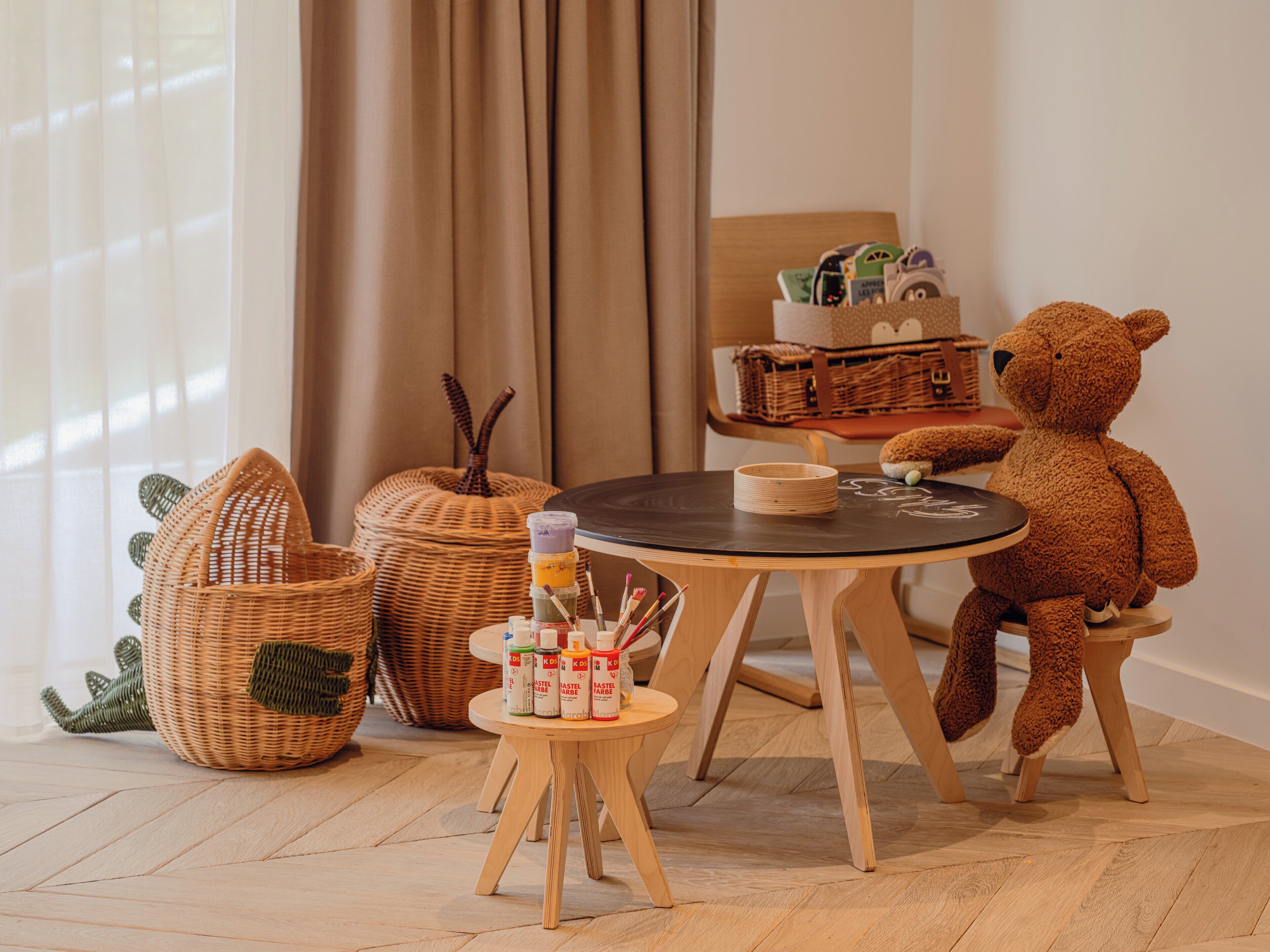 Una habitación acogedora con una mesa de madera, un osito de peluche y cestas de mimbre.