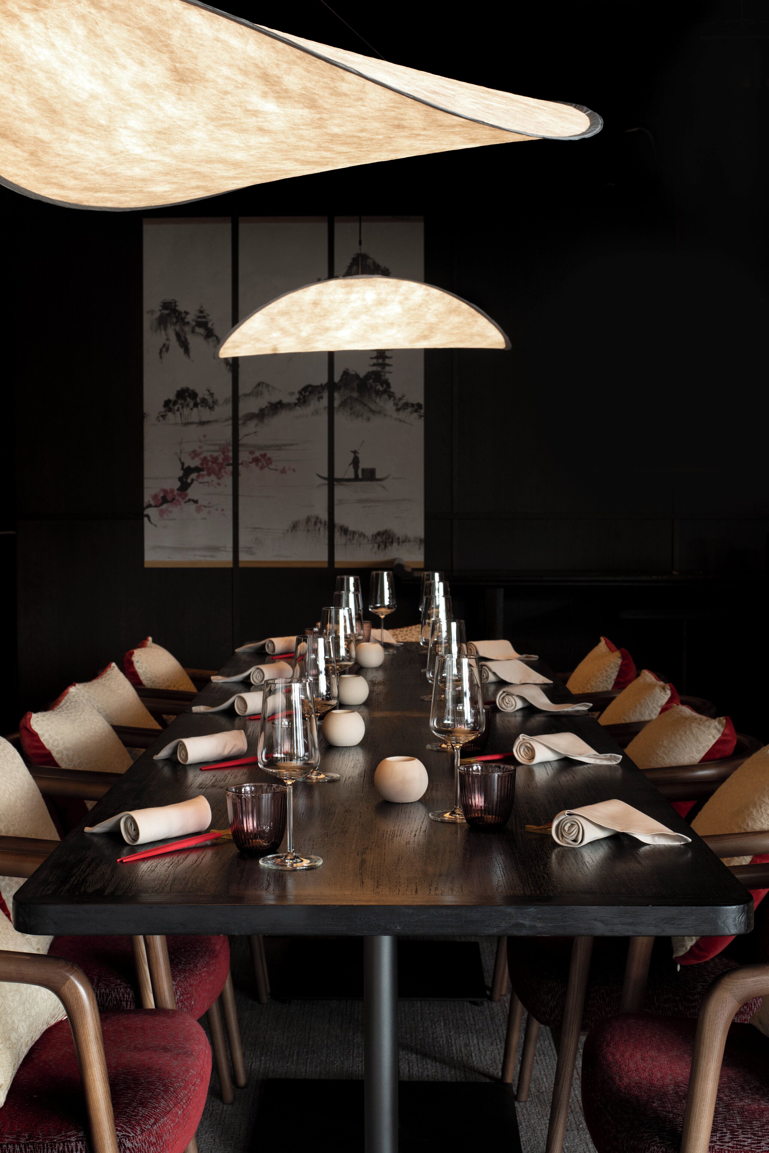 Une table à manger dressée avec de nombreux verres à vin, des serviettes pliées et des objets décoratifs.
