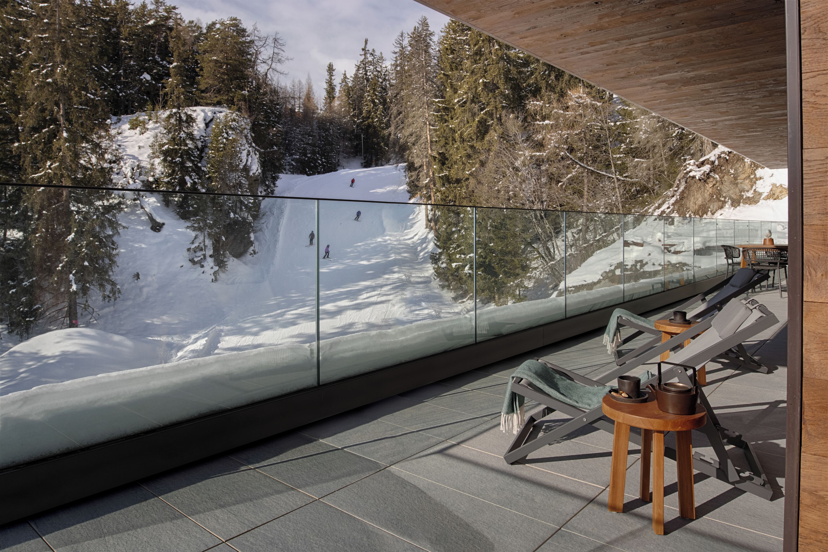 Une chambre moderne avec un mur de verre donnant sur un paysage montagneux enneigé.