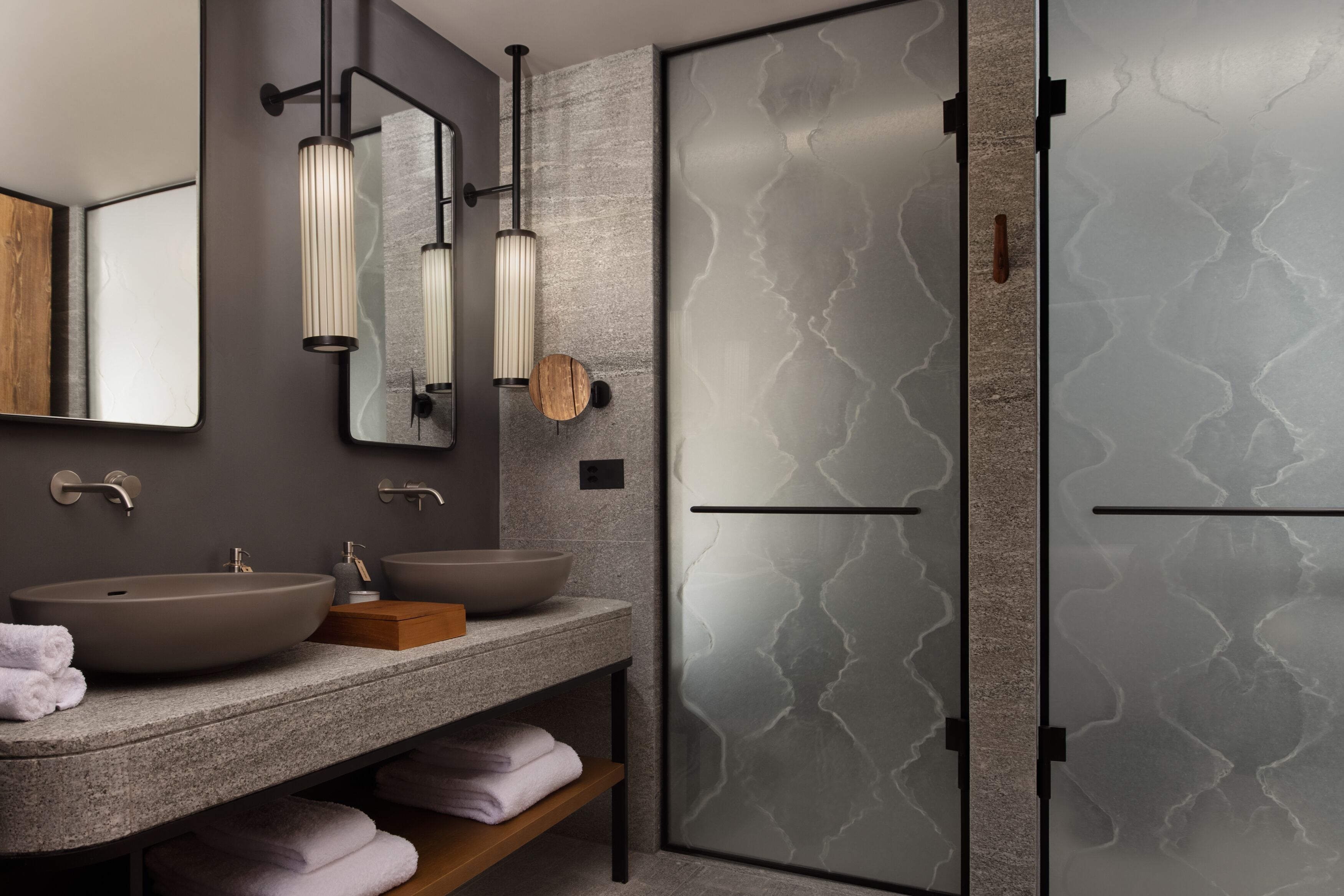A modern bathroom with a large mirror, two sinks, and a wooden shelf.