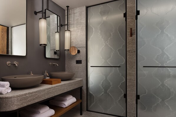 Un baño moderno con un espejo grande, dos lavamanos y un estante de madera.