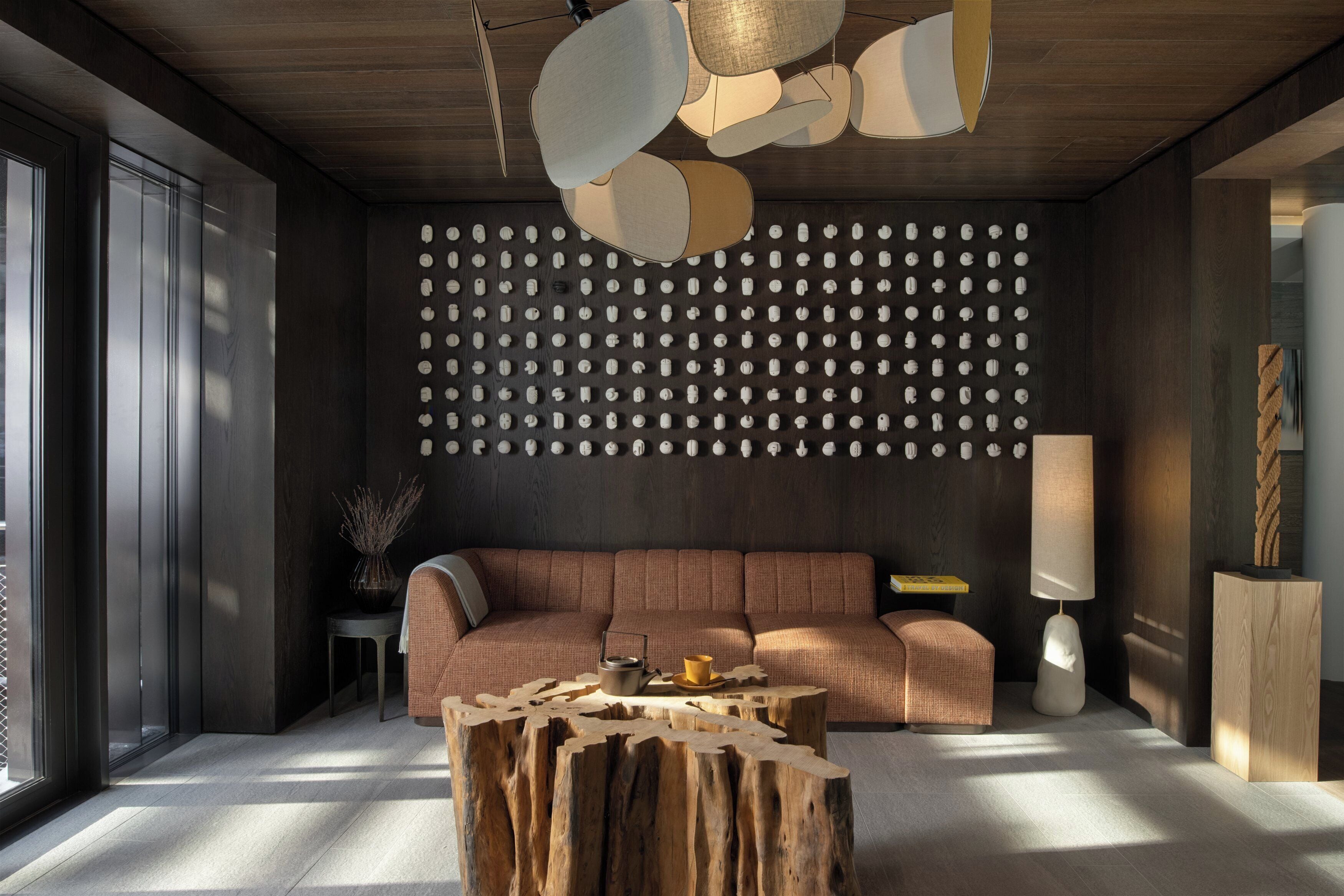A modern living room with a wooden ceiling, a patterned wall, a sofa, a coffee table, and a lamp.