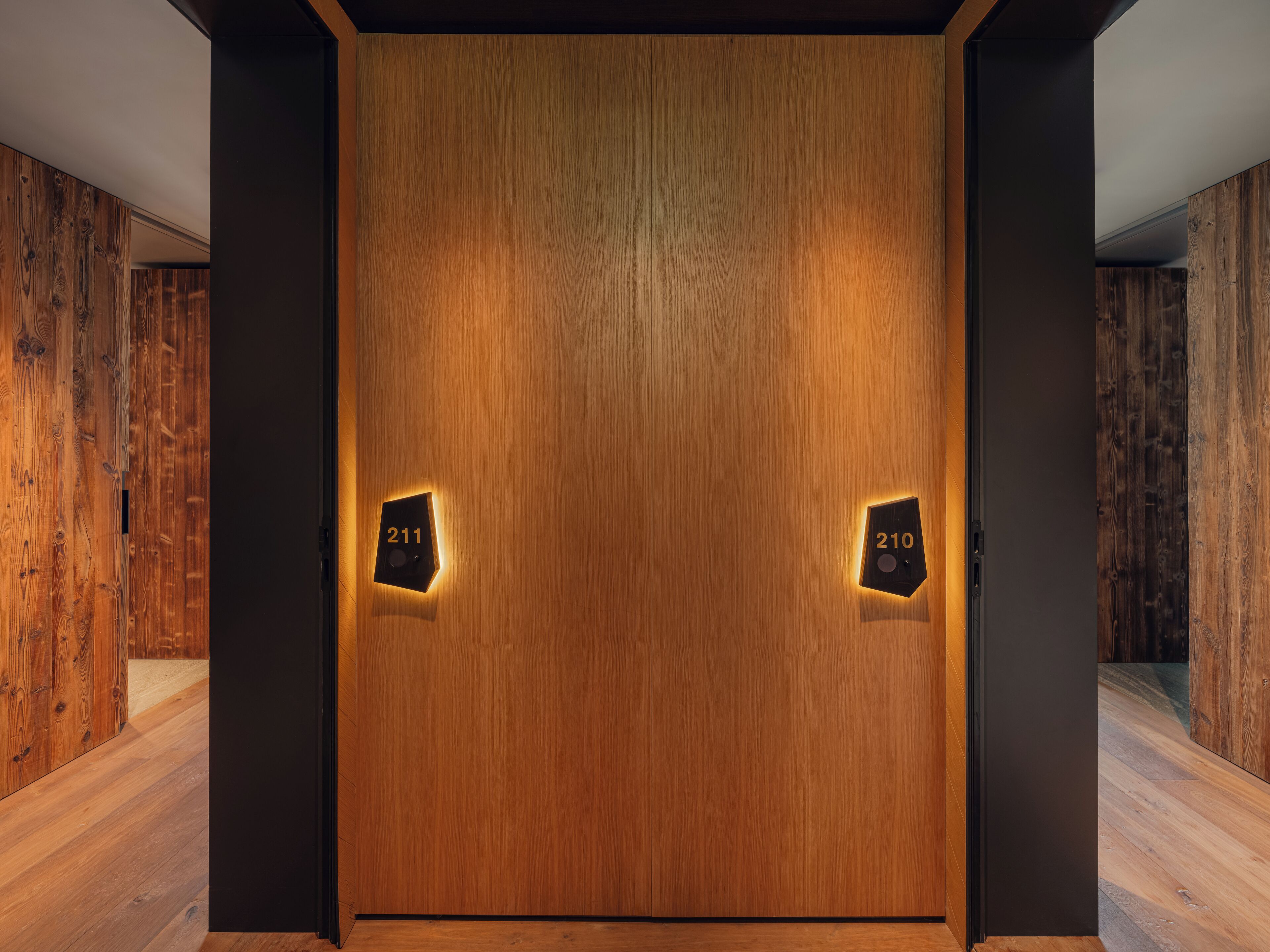 Una puerta de madera con dos placas iluminadas, con los números 211 y 210 que indican los números de habitación.