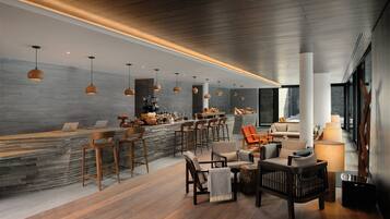 A modern interior with a bar area, seating, and a stone wall.