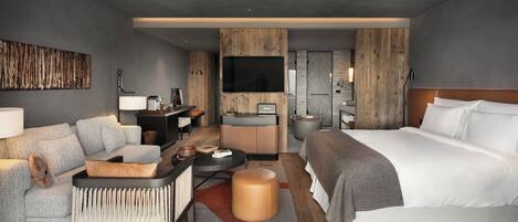 Una habitación de hotel moderna con sofá, cama, escritorio y televisión.
