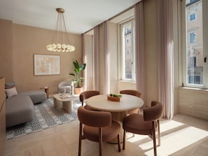A modern living room with a round table, brown chairs, a sofa, a coffee table, a potted plant, and a hanging light fixture.