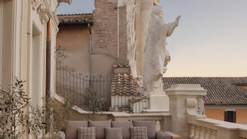 An outdoor seating area with a round table, chairs, and a sofa with cushions.