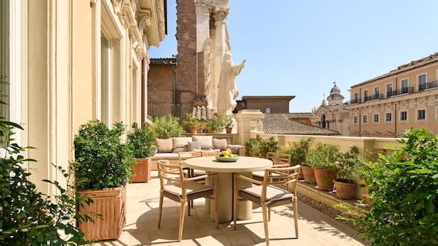 An outdoor seating area with a round table and chairs, surrounded by potted plants. - Six Senses Rome (Rome)