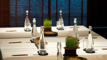A table set with clear glass bottles, a small potted plant, and a bowl of carrots.