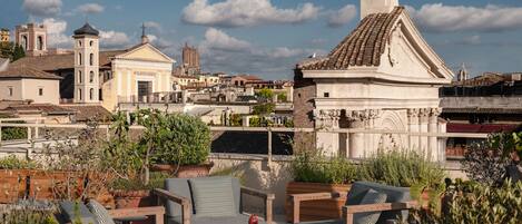 A rooftop terrace with outdoor seating, overlooking a historic cityscape with notable architecture.