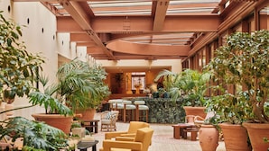 A spacious lobby with multiple seating areas, large potted plants, and a central bar area. - Six Senses Rome (Rome)