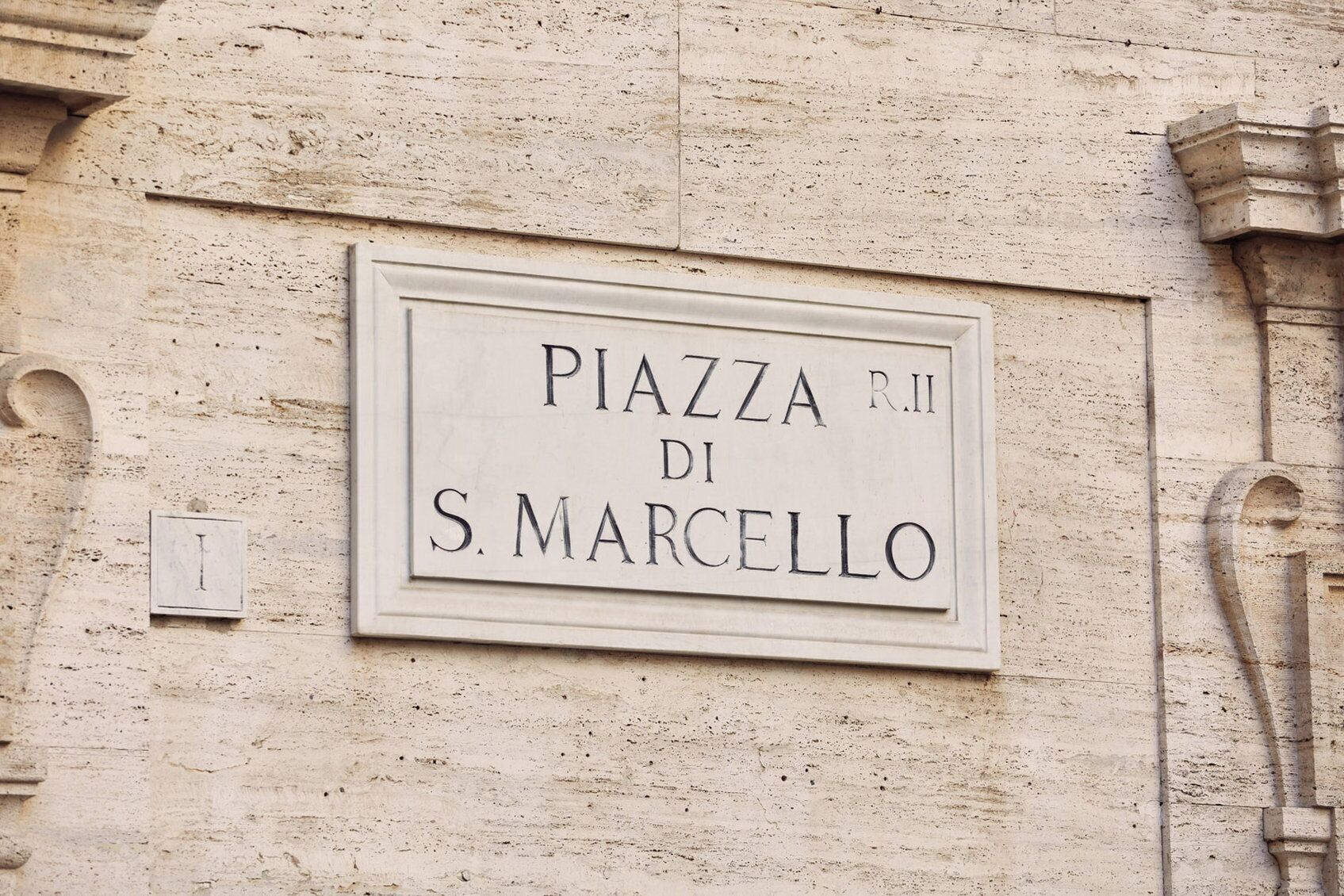 Una señal en la pared de un edificio que dice 'PIAZZA R.I DI S. MARCELLO'.