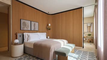 A modern bedroom with a large bed, bedside tables, a bench, a patterned rug, and a wooden wall panel.