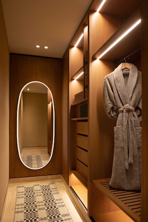 A modern bathroom with a wooden vanity, a mirror with a lighted frame, and a robe hanging on a rack.