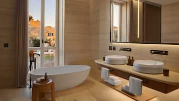 Un baño moderno con una bañera independiente, dos lavamanos redondos y un espejo grande.
