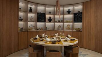 A round table with stools, surrounded by wooden cabinets with shelves containing kitchenware and decorative items.