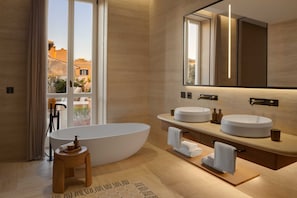 A modern bathroom with a freestanding bathtub, two sinks, and a large mirror.