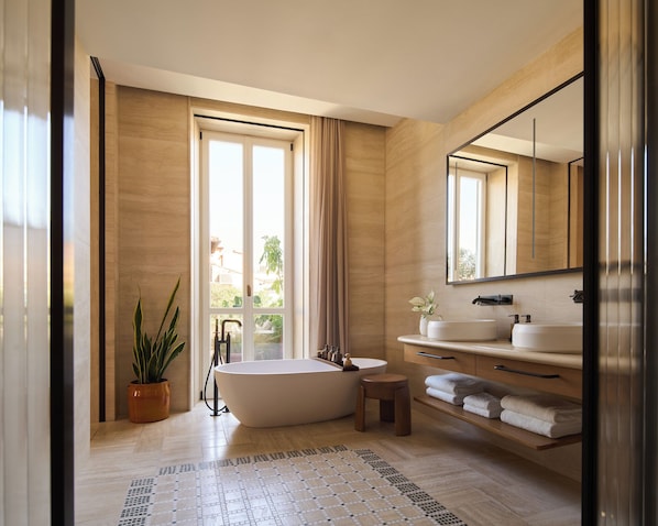 A modern bathroom with a freestanding bathtub, a large mirror, and a vanity with a sink and towel rack.