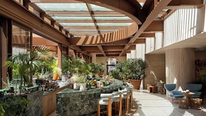 A modern bar area with a marble countertop, multiple bar stools, and a variety of potted plants. - Six Senses Rome (Rome)
