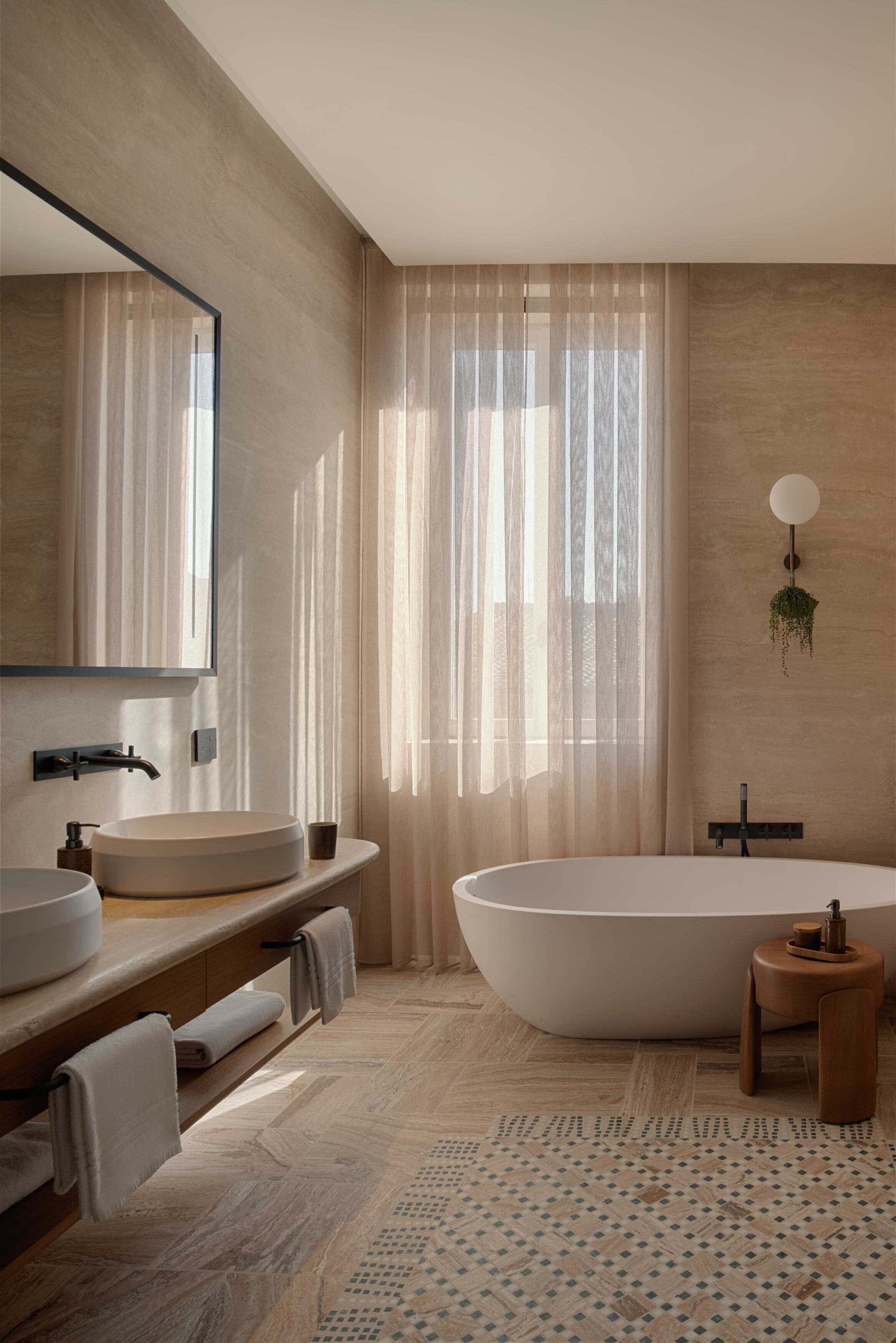 A modern bathroom with a freestanding bathtub, a round sink, and a mirror.