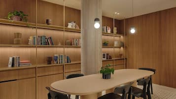 Un espace de salle à manger moderne avec une table ronde, des chaises noires, des étagères en bois et des luminaires suspendus.