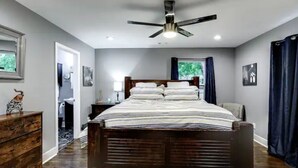 A bedroom with a wooden bed, a ceiling fan, a nightstand, and a dresser.