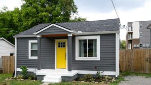 A single-story house with a yellow front door, white trim, and a small front porch.