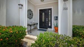 Une porte d’entrée avec une porte noire, une boîte aux lettres et une plaque indiquant le numéro de la maison.