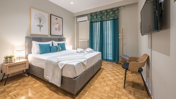 A modern bedroom with a bed, bedside table, and a TV mounted on the wall. - Elegant Mavili Suite by Cloudkeys (Athens)