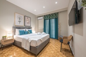 Een moderne slaapkamer met een bed, nachtkastje en een aan de muur bevestigde televisie.